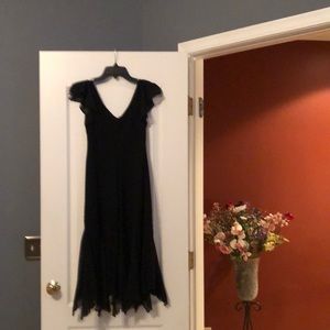 Black cocktail dress with flutter sleeves, handkerchief hem, sequins on hem.